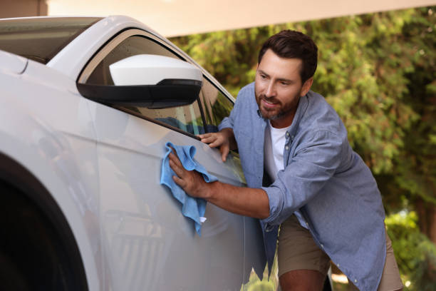 istock Bearded man cleaning car door with rag outdoors 1932661237