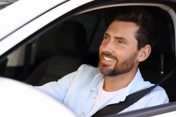 istock Enjoying trip. Handsome bearded man driving his car, view from outside 1932662336