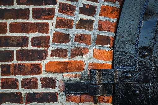 Detail of hinges metal door on brick wall in Red Hook, Brooklyn, New York