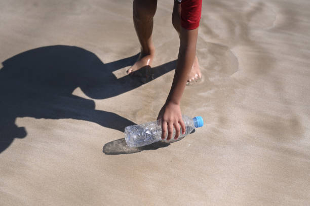 istock Close Up Picking up bottle trash from the sea 1932692951