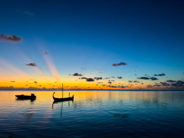At the ocean in sunset with boat on sunny Maldive island.