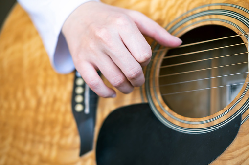 Hand is playing the acoustic guitar, close-up. Fingerpicking, fret, fretboard, guitar lesson