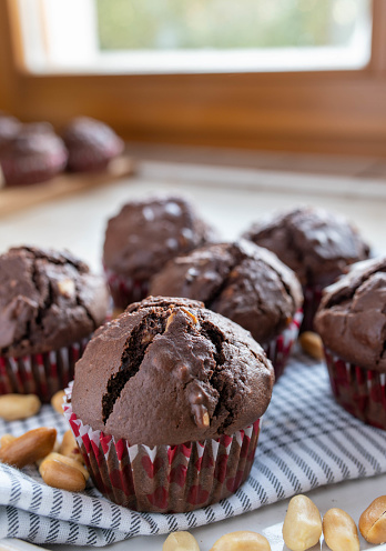 Delicious homemade chocolate muffins with peanuts on kitchen counter. Closup