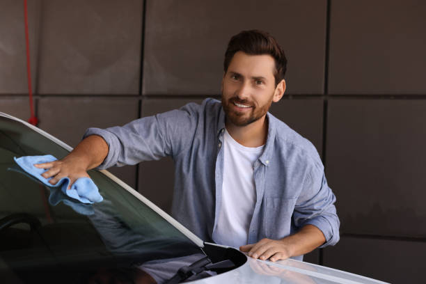 istock Smiling man cleaning car windshield with rag outdoors 1932715164