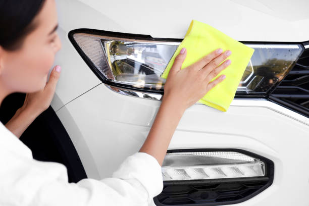 istock Woman cleaning car headlight with rag, closeup view 1932715707