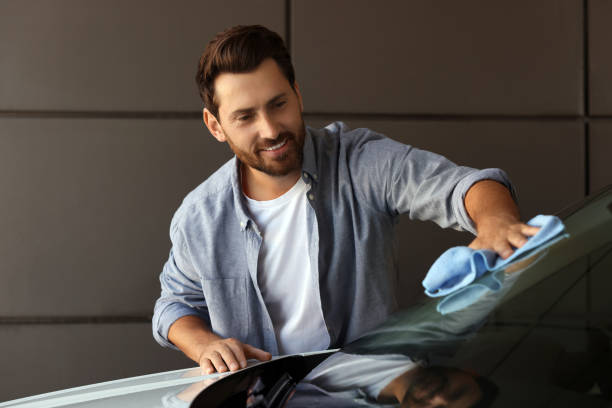 istock Smiling man cleaning car windshield with rag outdoors 1932715739