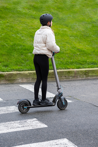 Urban crossing on an electric scooter. Young girl moves with agility through a pedestrian crossing on their electric scooter, demonstrating the convenience and mobility that these devices bring to urban life. Concept of electrical mobility in the modern city.