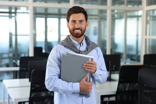 istock Handsome happy man with folders in office 1932735787