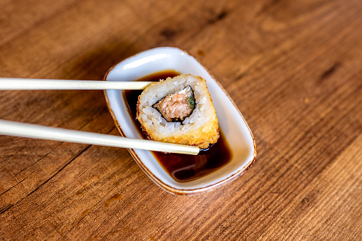 Take a roll with chopsticks and dip it in soy sauce
