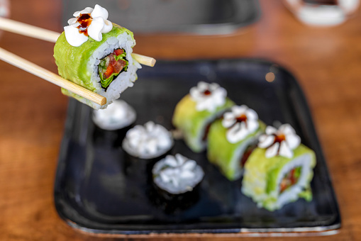 Sushi isolated on white background. Sushi salmon nigiri in chopsticks. Holding the chopsticks in hand. Japanese food.