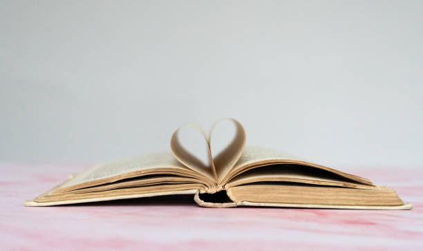 istock stack of old books with an old book open on top and pages that form a heart 1932750294