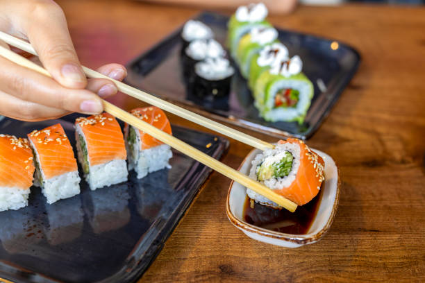 chopstick with sushi roll and soy sauce - sushischotel stockfoto's en -beelden