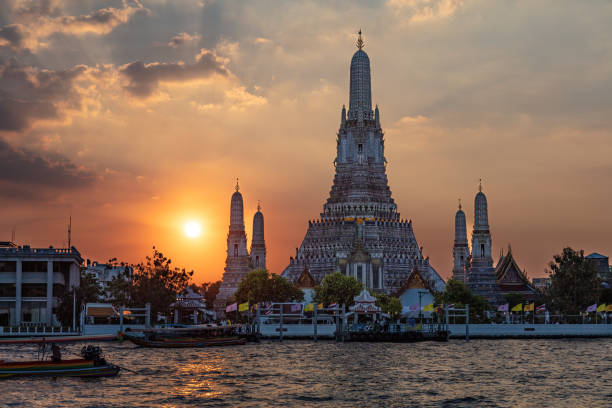 istock Wat Arun Temple, Bangkok. Sun setting behind temple, river in foreground. 1932809221