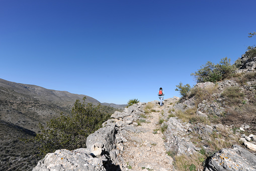 Woman hiking up steep ancient Mozarabic Trail in the Vall de Laguart, Benimaurell, Alicante Province, Spain
