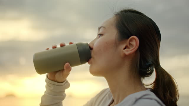 Sport woman drinking water with reusable mug
