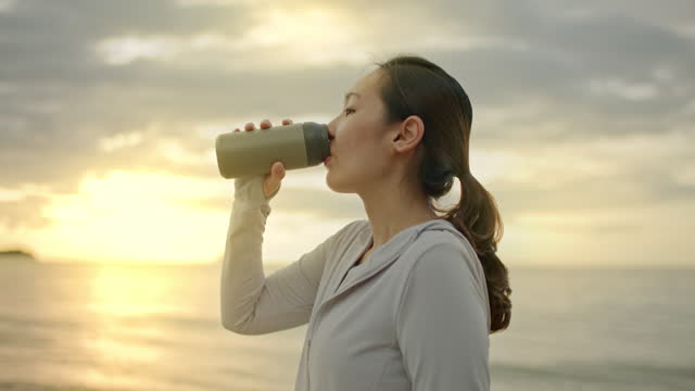 Sport woman drinking water with reusable mug