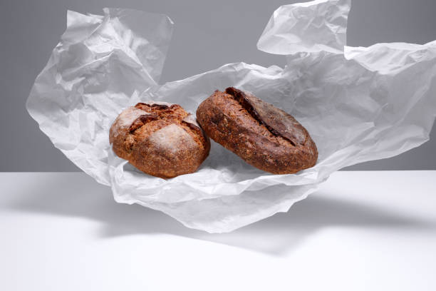 istock Two loaf rye bread on a flying crumpled parchment paper. 1932843563