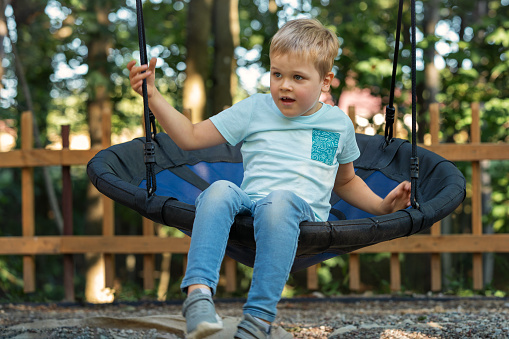 A cute child in a hammock swing with a surprised expression, the boy saw something.