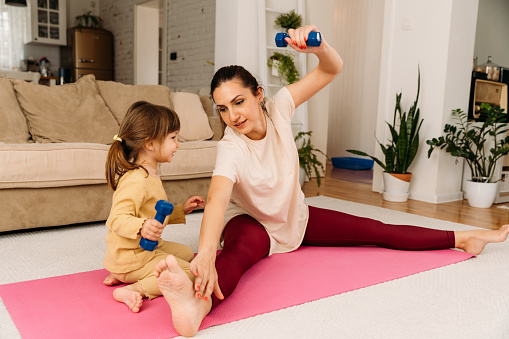 Mother and child having fun while stretching and exercise together at home