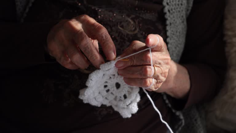 Senior woman knitting on sofa