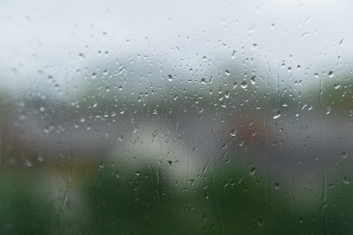 Mesmerizing raindrops gracefully cascading down the window on a rainy day, capturing the beauty of a tranquil and soothing atmosphere.