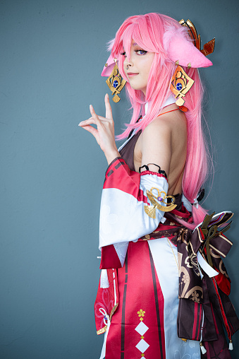 A Female cosplayer in a pink anime costume wearing pink hair