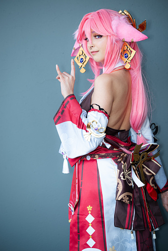 A Female cosplayer in a pink anime costume wearing pink hair