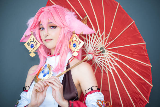 female cosplayer in a pink anime costume wearing pink hair - cosplay de anime fotografías e imágenes de stock