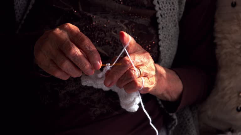 Senior woman knitting on sofa