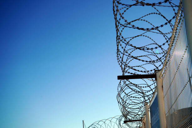 istock Barbed wire against a blue sky - stock photo 1932988610