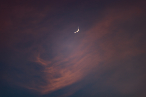 Crescent moon with pink sky at sunset.