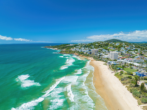 An aerial of the foamy waves of the ocean hitting the sandy shore in Coolum, Sunshine Coast QLD