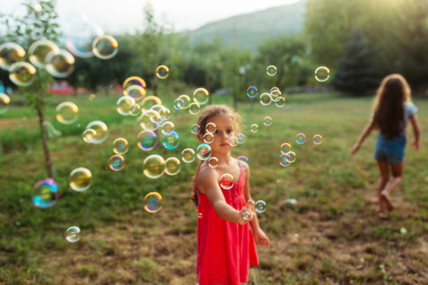 istock Little girl having fun catching soap bubbles in the yard 1932993338