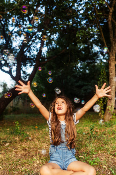 istock Little girl having fun catching soap bubbles in the yard 1932997519
