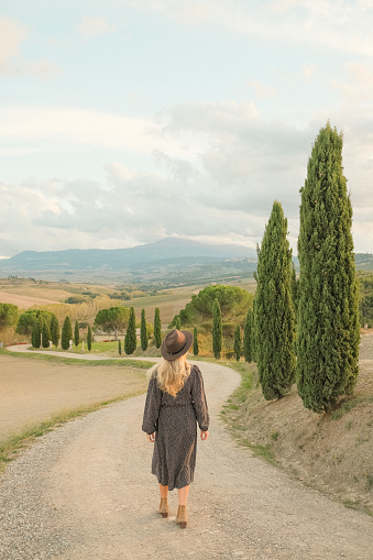 Young woman walks down country road in late summer, early autumn