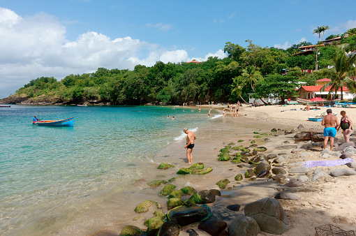 Martinique, Les Trois-Ilets - Novembre 23, 2023 : Tourists swimming and tanning on a sunny day at the beach of Anse Dufour, also a fisherman spot for locals.