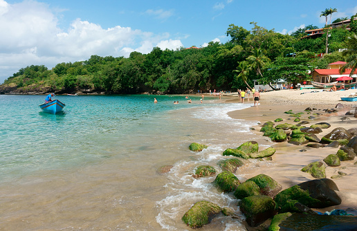 Martinique, Les Trois-Ilets - Novembre 23, 2023 : Tourists swimming and tanning on a sunny day at the beach of Anse Dufour, also a fisherman spot for locals.