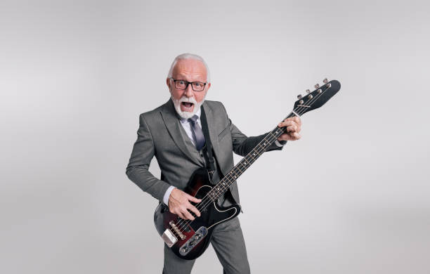 istock Senior businessman with mouth open singing ecstatically and playing guitar over white background 1933049936