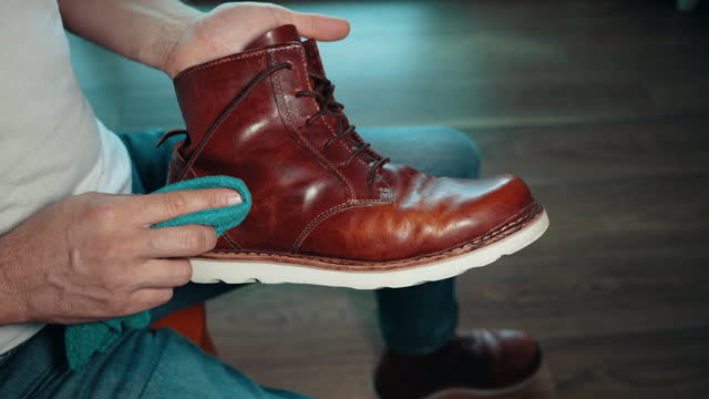 Man waxing, rubbing, shining and polishing leather boot shoes