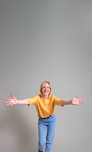 Excited young businesswoman smiling and welcoming with arms outstretched against white background
