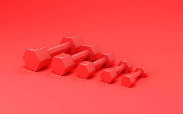 istock Red Plastic Dumbbells Sitting on Soft Red Background 1933064527