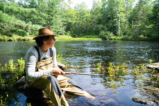 A teenaged male fisherman enjoying a beautiful day out fishing for trout in Nova Scotia