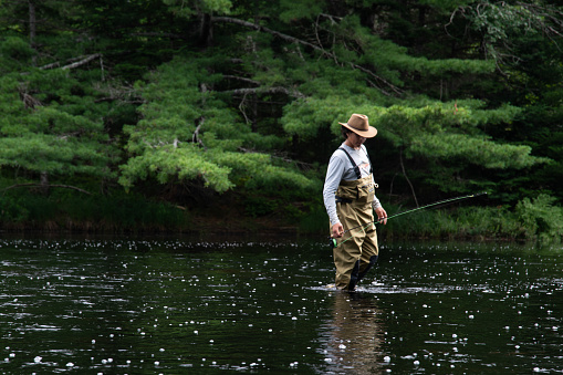 Man on a river bank caught a fishing with a fishing rod.