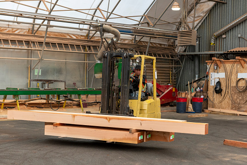 Forklift carries wood beams across factory floor