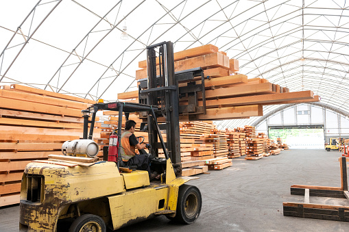 Forklift carries wood beams across factory floor