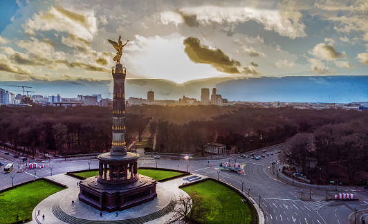 Fantastic sunset Drone point of view  on Victory column (67m) of 1864. Winter forest of Tiergarten of Berlin - now Christmas week
 (or several days before). Grosser Stern and cars waiting at the intersection