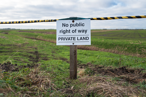 Shallow focus of a Private Land sign in rural East Anglia. Known for trespassing due to the nearby public footpath, the land owner has now blocked off the entrance.