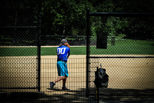 A man playing baseball on a sunny day at Central Park.