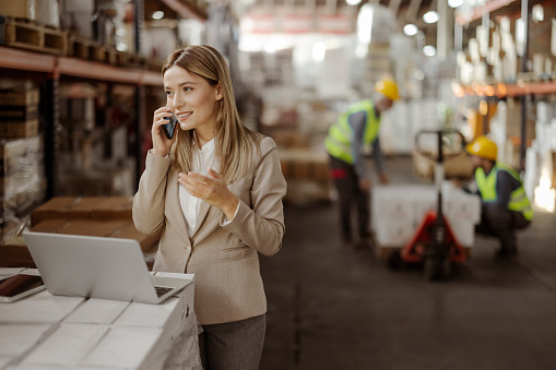 Female Warehouse Manager Calling on Smartphone at Warehouse. Wholesale, Logistic, Business, Export and People Concept
