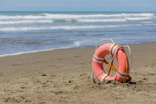 istock Lifebuoy on a deserted beach over blue sky. 1933224991